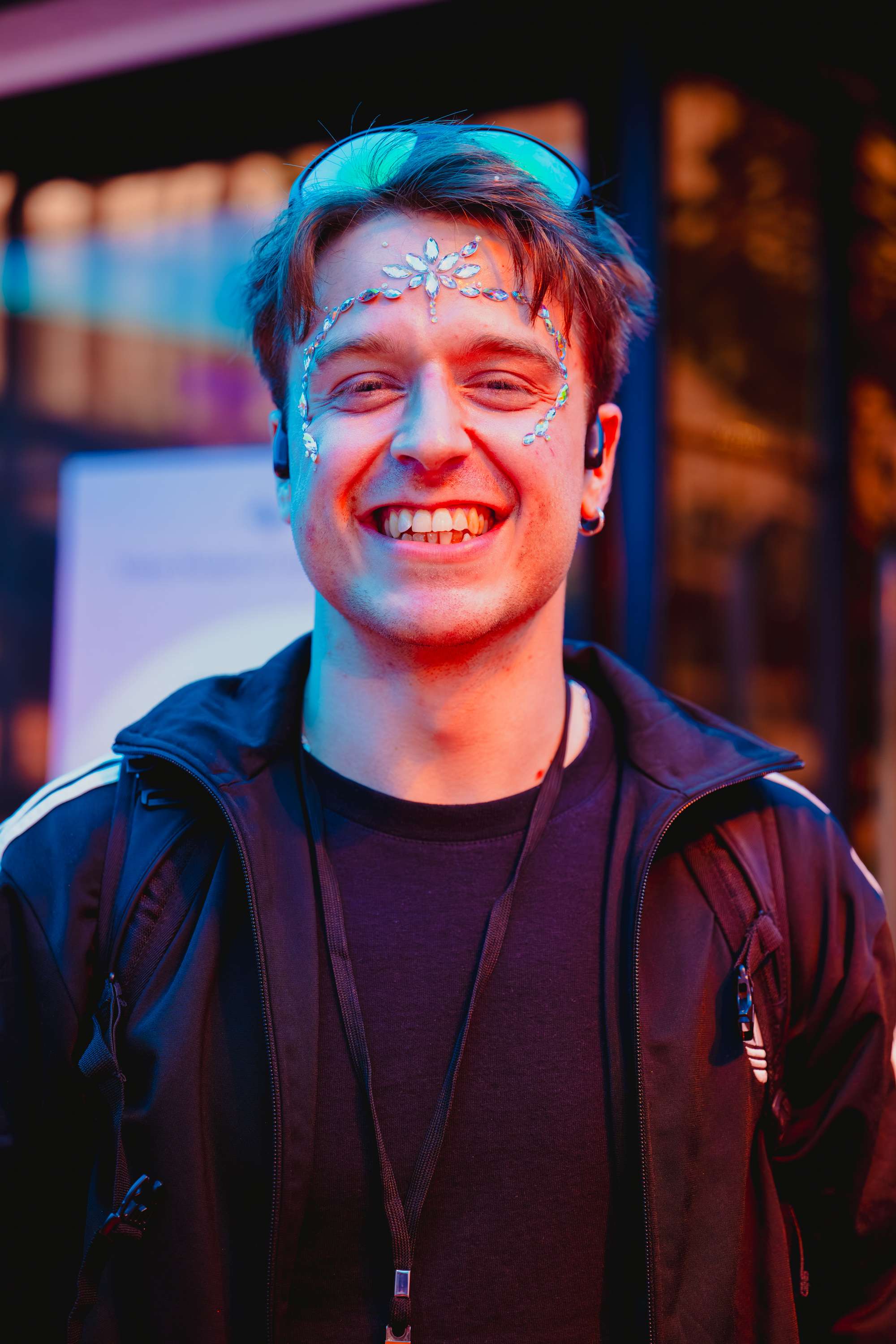 Samuel Nellessen smiling with gemstone face decoration at an evening event.